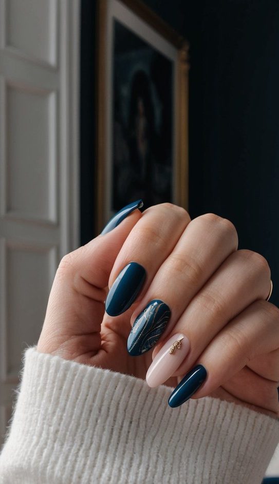 A hand with glossy dark teal nails, a blush pink accent nail adorned with a small gold branch charm, and a single nail with a silver-veined leaf design for an elegant wedding look.