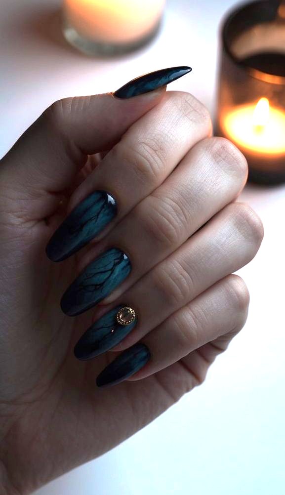 Deep, moody nail designs cast eerie shadows in dim candlelight