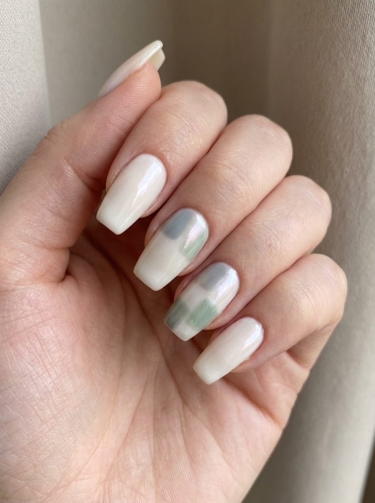 Square-shaped pearl wedding nails painted in glossy ivory, accented with blended sage green and pearlescent silver patches on the middle and ring fingers.